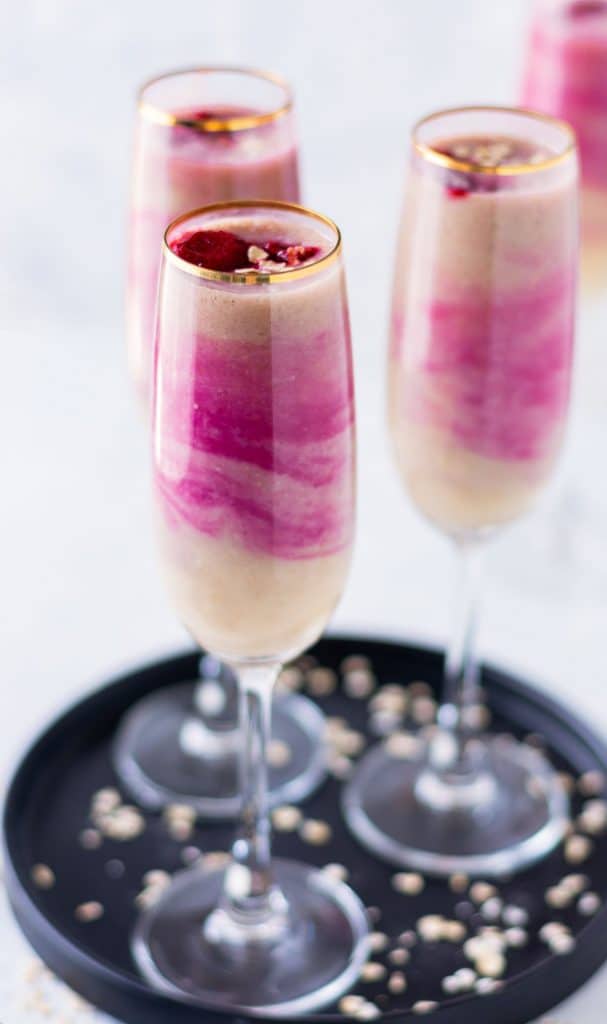 3 raspberry ombre smoothies served in tall skinny glasses on top of a black serving tray