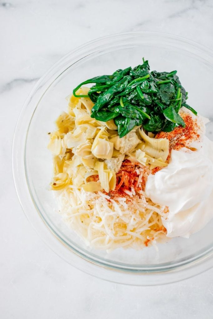 artichokes, baby spinach, cheese, sour cream and spices added to a large glass bowl