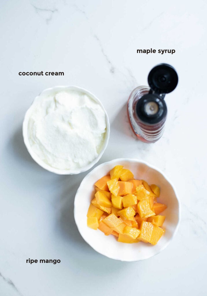 overhead ingredient shot of ripe mango, coconut cream and maple syrup