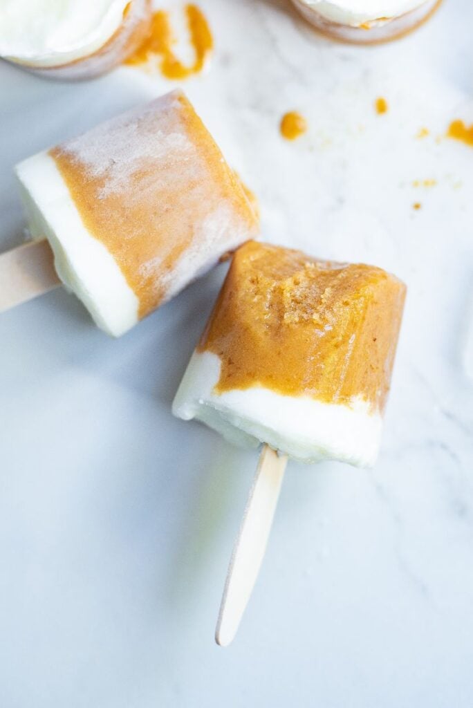 Up close shot of coconut and mango popsicles against a white background