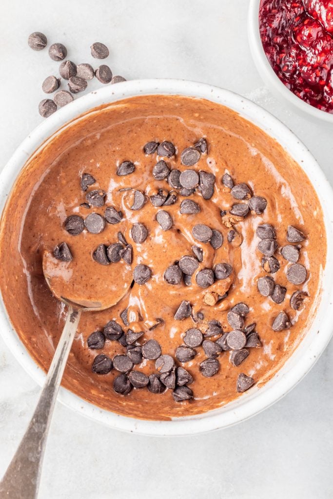 A large white bowl containing a chocolate batter topped with chocolate chips