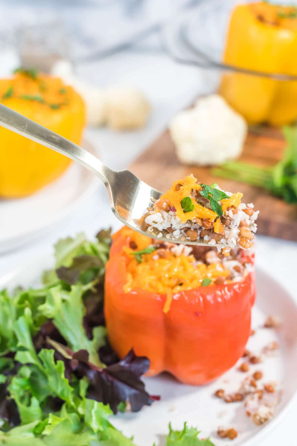 Up close shot of a fork containing a cauliflower rice and cheese mixture from a red bell pepper