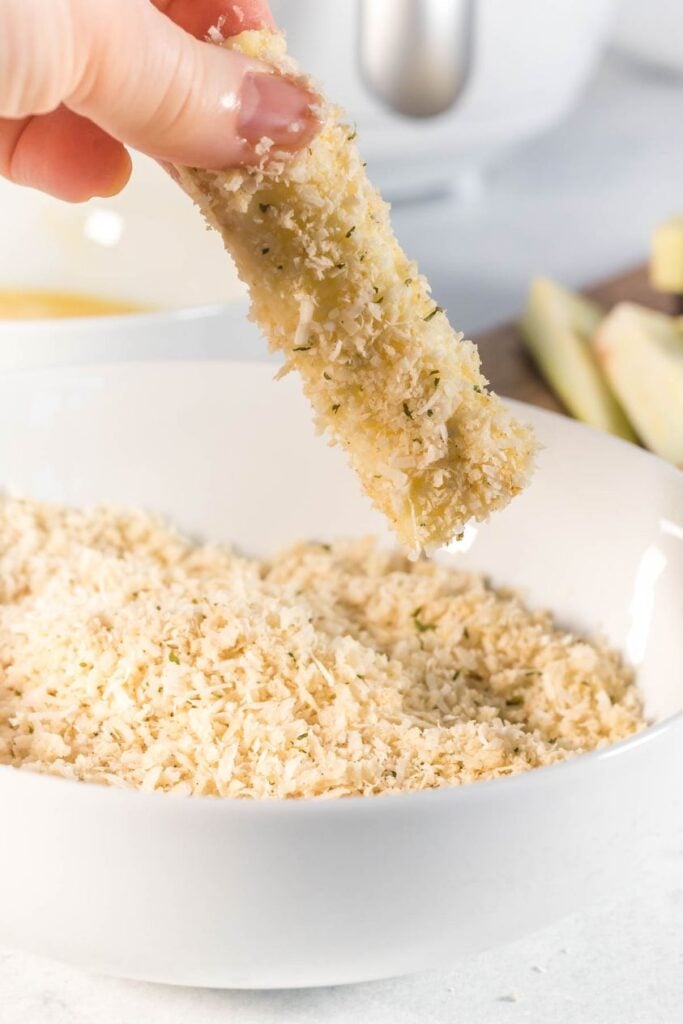 eggplant sticks being dipped in an a panko mixture
