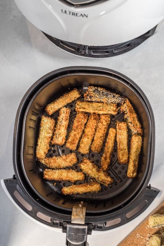 crispy eggplant fries sitting in the basket of an air fryer