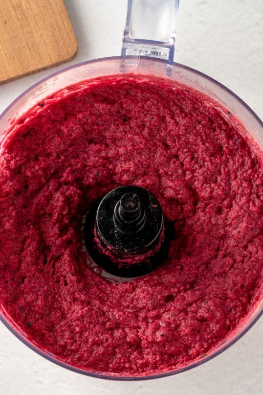 Overhead shot of the bowl of a food processor containing a hot pink dip