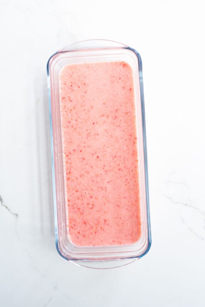 blended strawberries in a glass ice cream container