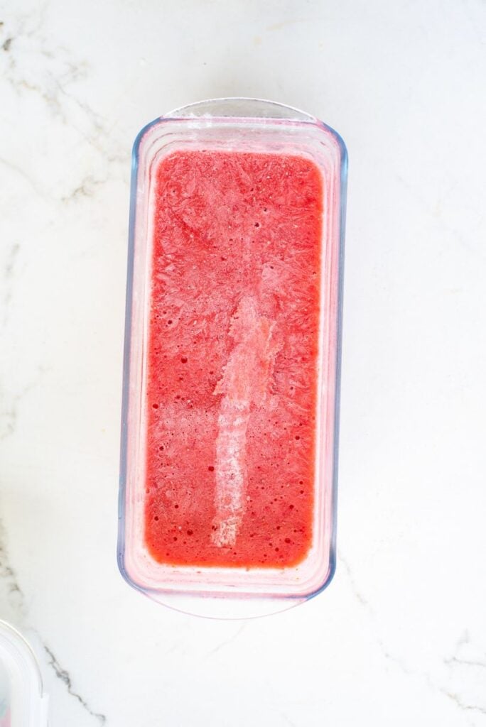 blended frozen strawberries in a glass ice cream container