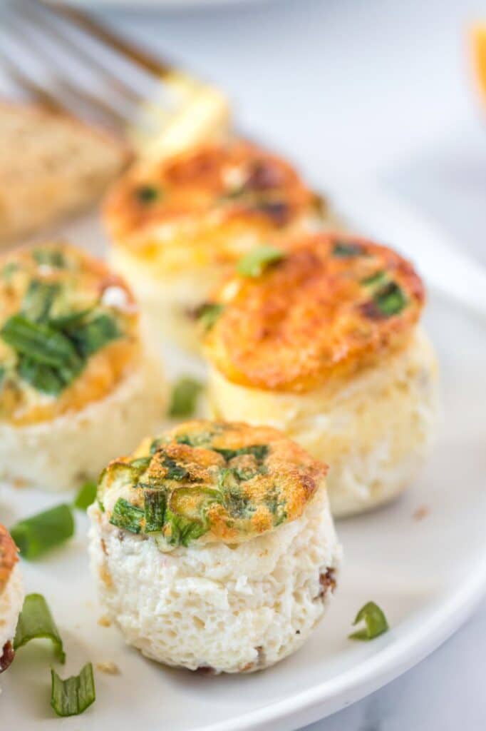 Up close shot of egg muffins served on a white plate with a sprinkle of green onions