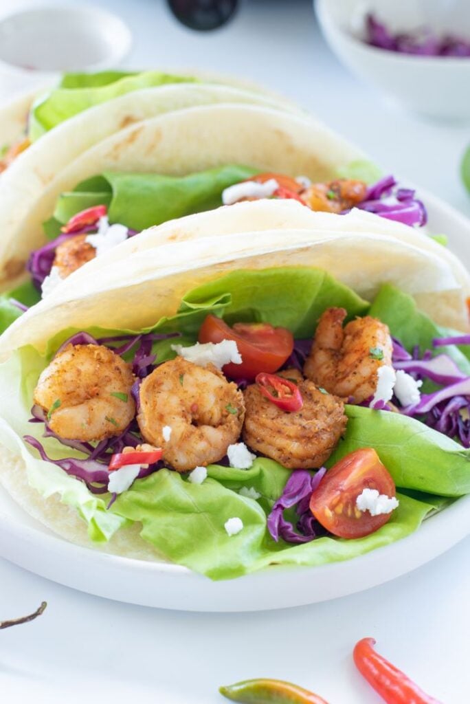 Air fryer shrimp served in a flour tortilla with lettuce, purple cabbage and other taco toppings