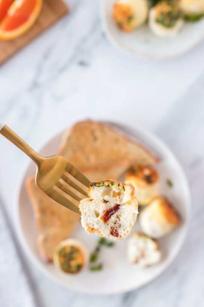 An egg bite cut in half on a fork showing flecks of sundried tomato throughout