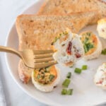 Air fryer egg white bites cut in half and on a fork, served on a white plate with a side of toast