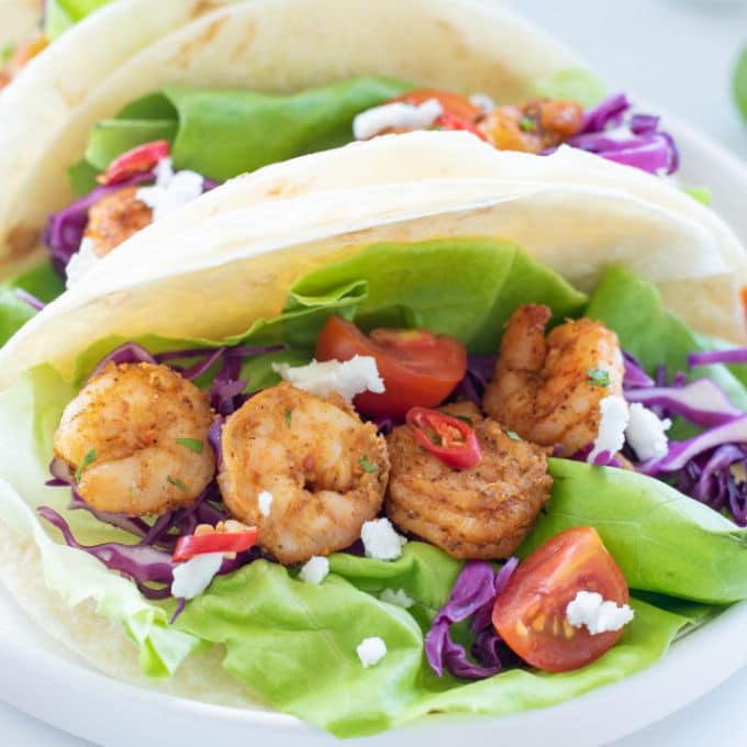 air fryer shrimp tacos loaded with lettuce, purple cabbage and cilantro