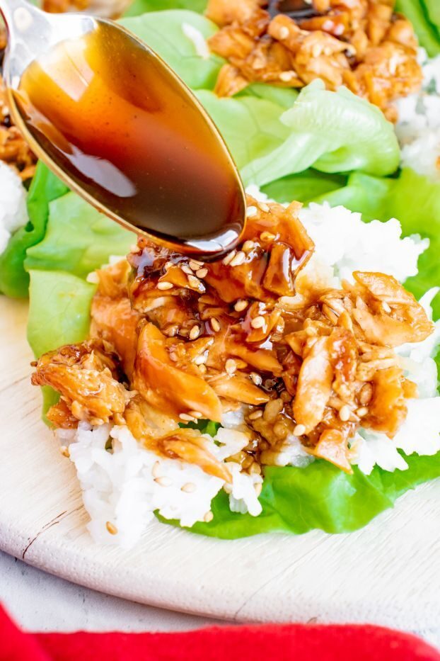 Overhead shot of teriyaki sauce being poured on top of salmon lettuce wraps