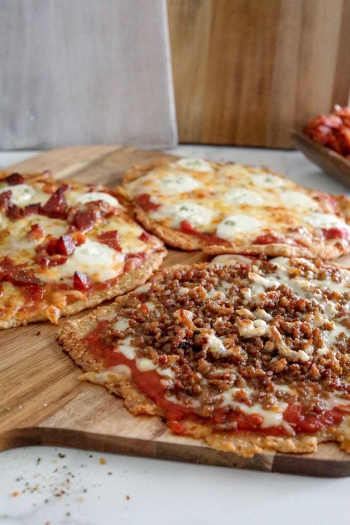 3 cooked pizzas served on a wooden board