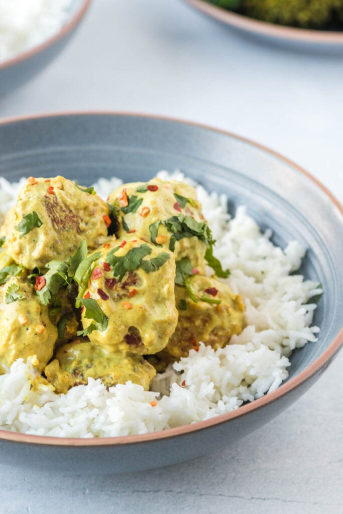 meatballs and curry served with rice in a light blue bowl