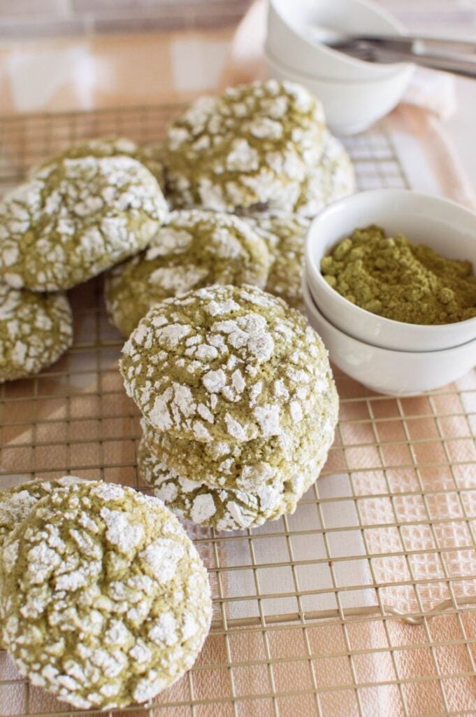 Matcha cookies on a wire cooling rack with a small bowl of matcha in the background