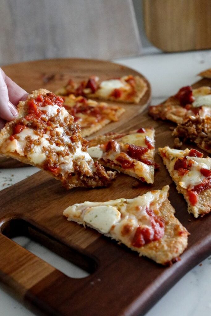 individual slices of low carb pizza served on a long wooden board