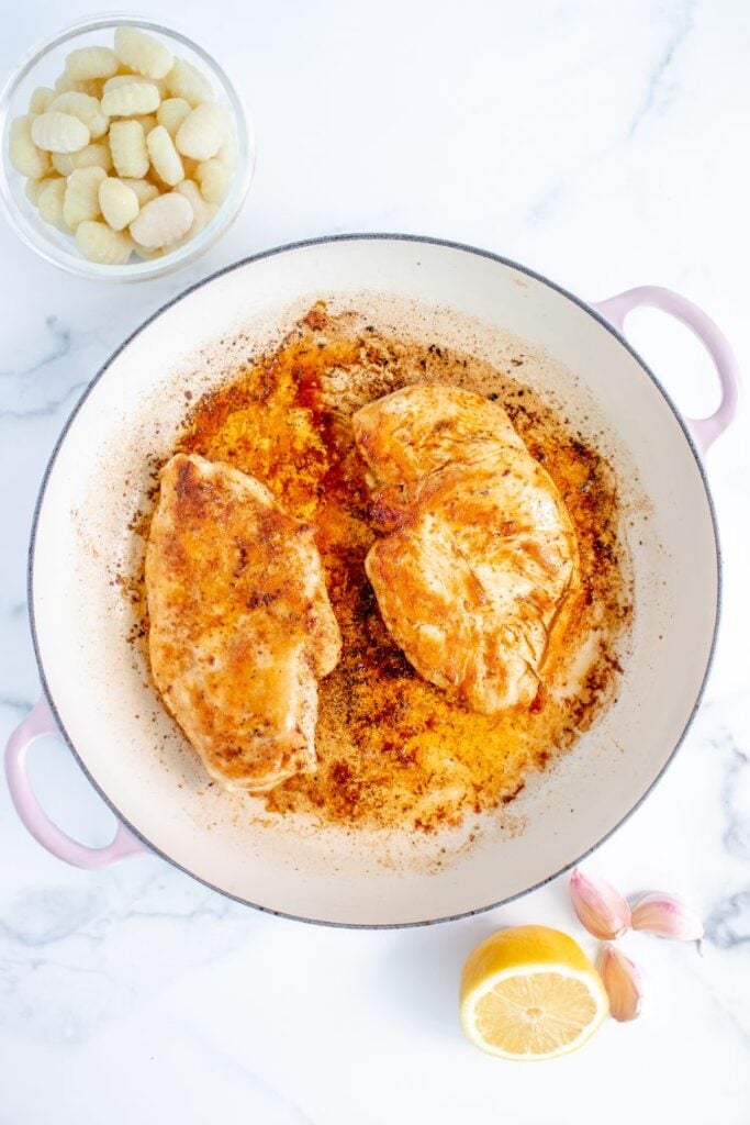 Process shots for cooking seasoned chicken breasts in a large white skillet