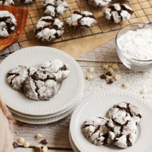 peppermint and chocolate cookies loaded onto a white serving plate with extra cookies on a cooling rack in the background