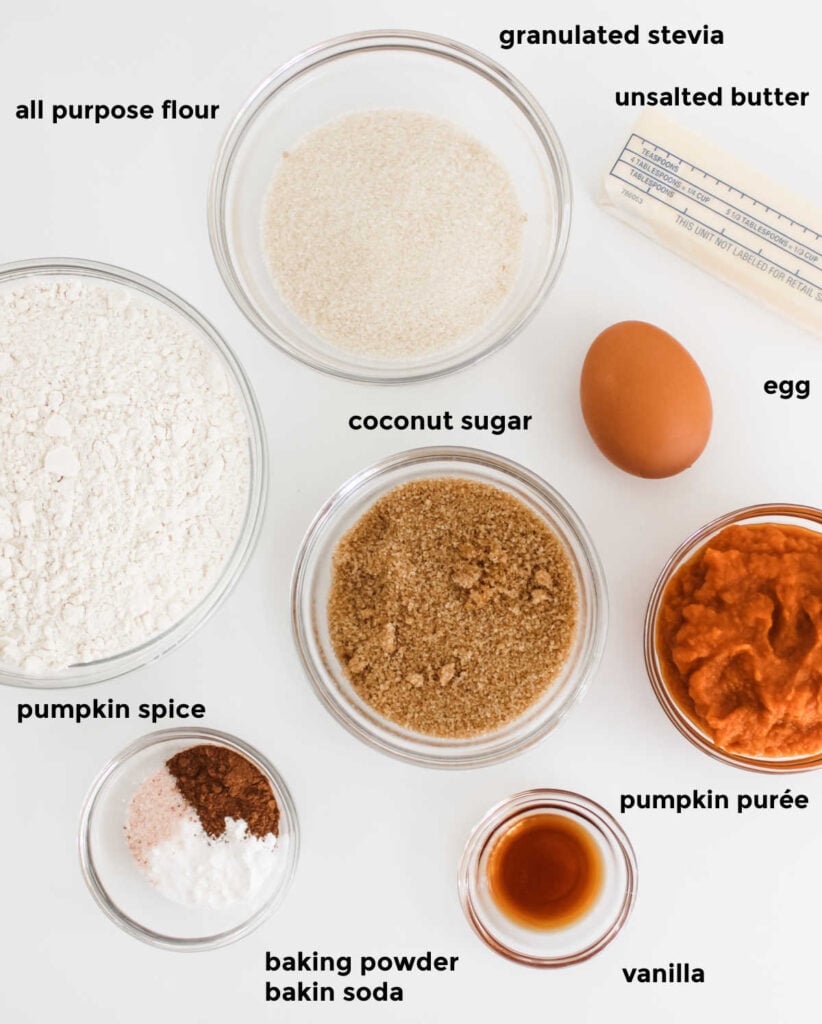 An overhead ingredient shot of all the ingredients required for pumpkin cookies arranged in small glass bowls