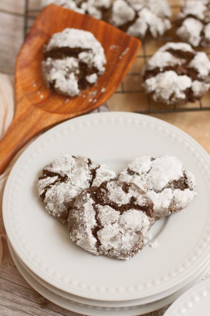 peppermint and chocolate cookies loaded onto a white serving plate with extra cookies on a cooling rack in the background