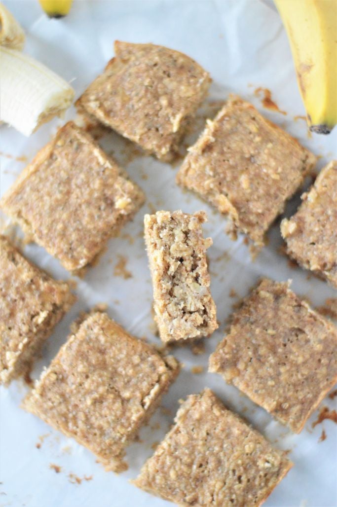 Banana protein bars cut into equally sized squares on parchment paper with one bar on its side
