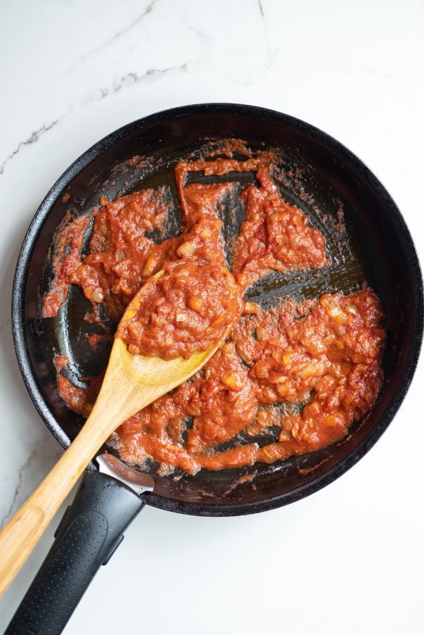 Tomato pasta being sautéed in a black saucepan