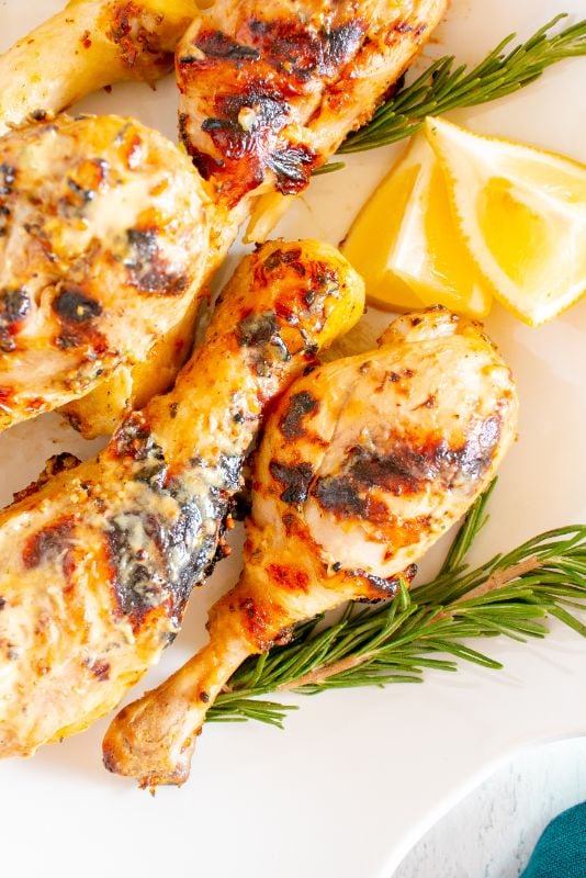 Chicken drumsticks grilled on the outdoor bbq and served with lemon wedges and fresh rosemary sprigs