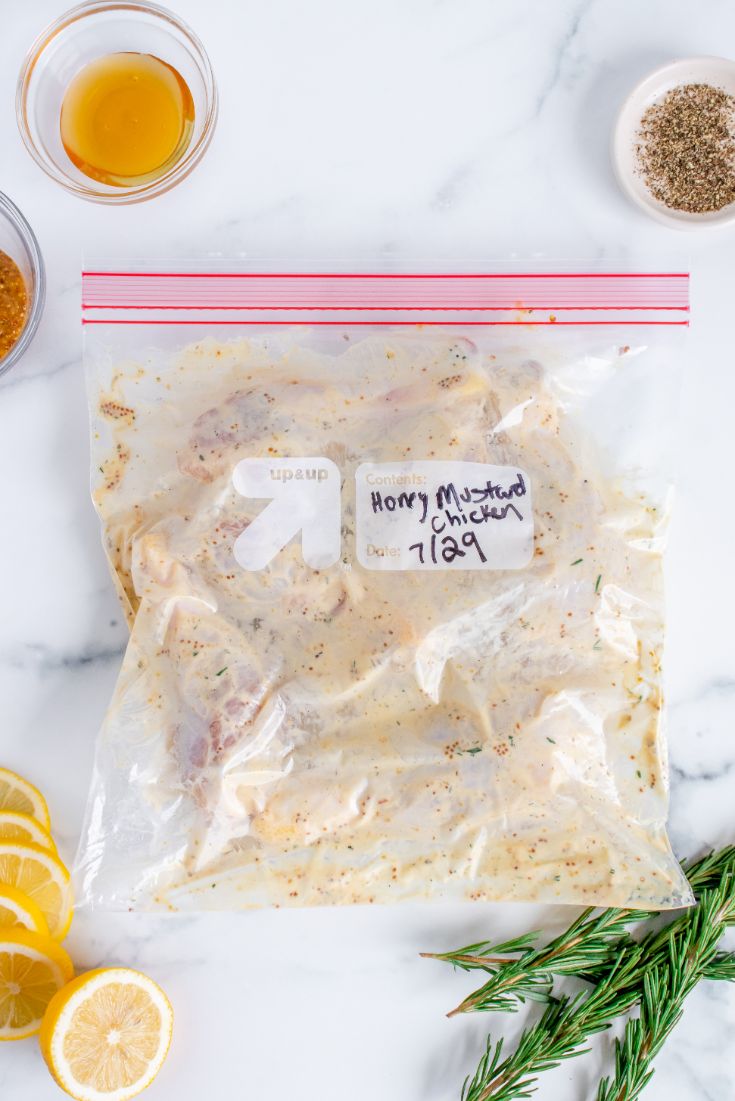 Meal prepped chicken drumsticks marinating in a honey mustard sauce in a ziploc bag