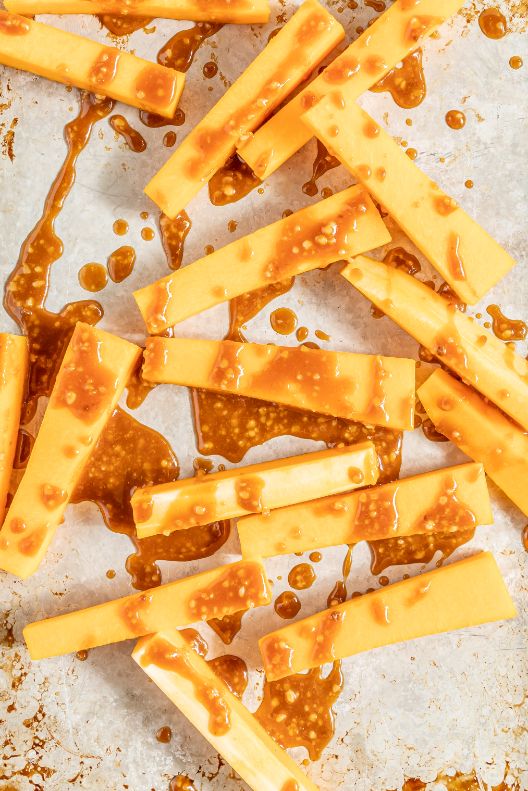 Rectangles of chopped pumpkin on a baking sheet with a drizzle of miso sauce on top