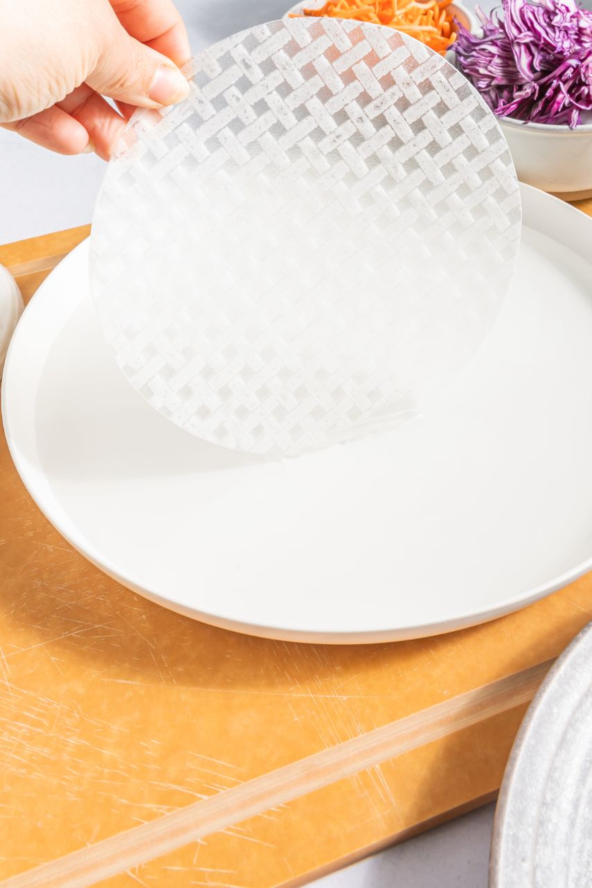 A fresh rice paper sheet being dipped in cold water to soften it