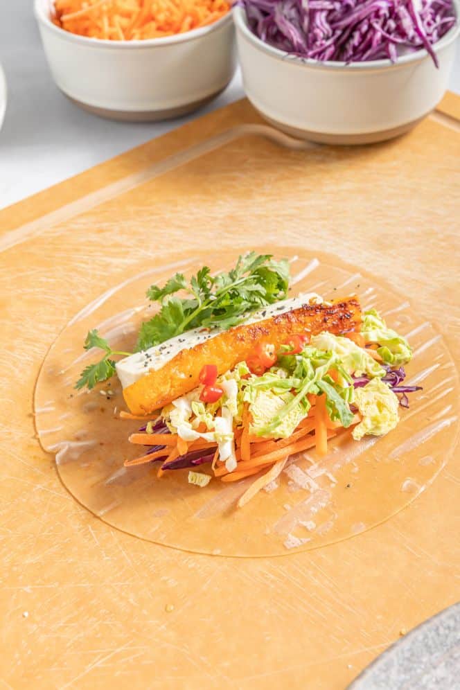 Vegetables arranged on a softened rice paper sheet prepped for making veggie summer rolls