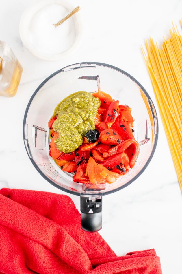 Roasted red peppers and basil pesto added to the bowl of a food processor