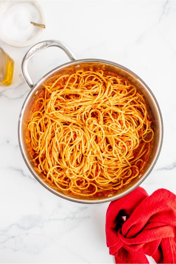 Pasta being cooked in a large pot with a red sauce