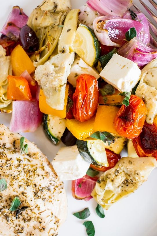 Perfectly seasoned greek vegetables and chicken served on a white plate