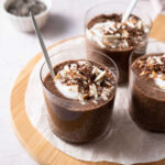 Chocolate chia seed puddings served in small glasses and topped with yogurt, chopped almonds and extra chocolate