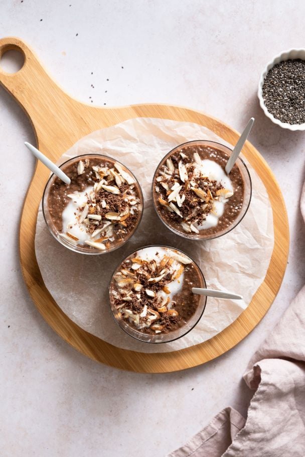 chia seed pudding made with cocoa served in small mason jars and topped with yogurt, almonds and shaved chocolate