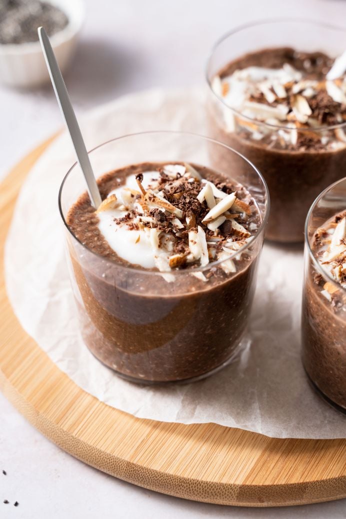 Chocolate chia seed puddings served in small glasses and topped with yogurt, chopped almonds and extra chocolate