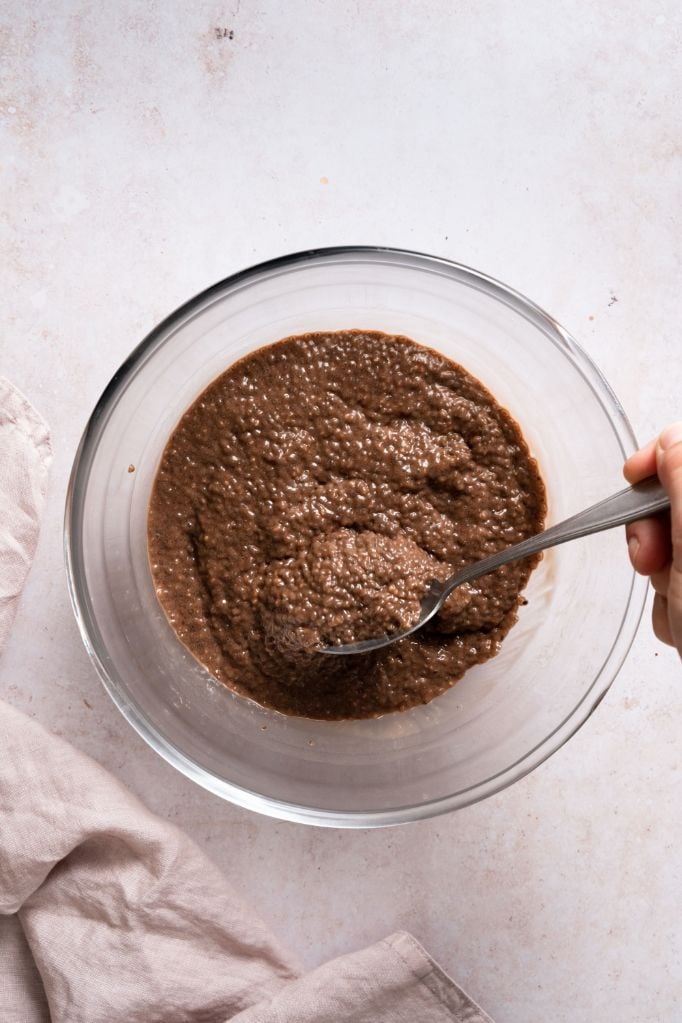 Thick chocolate chia seed mixture being mixed in a large glass bowl