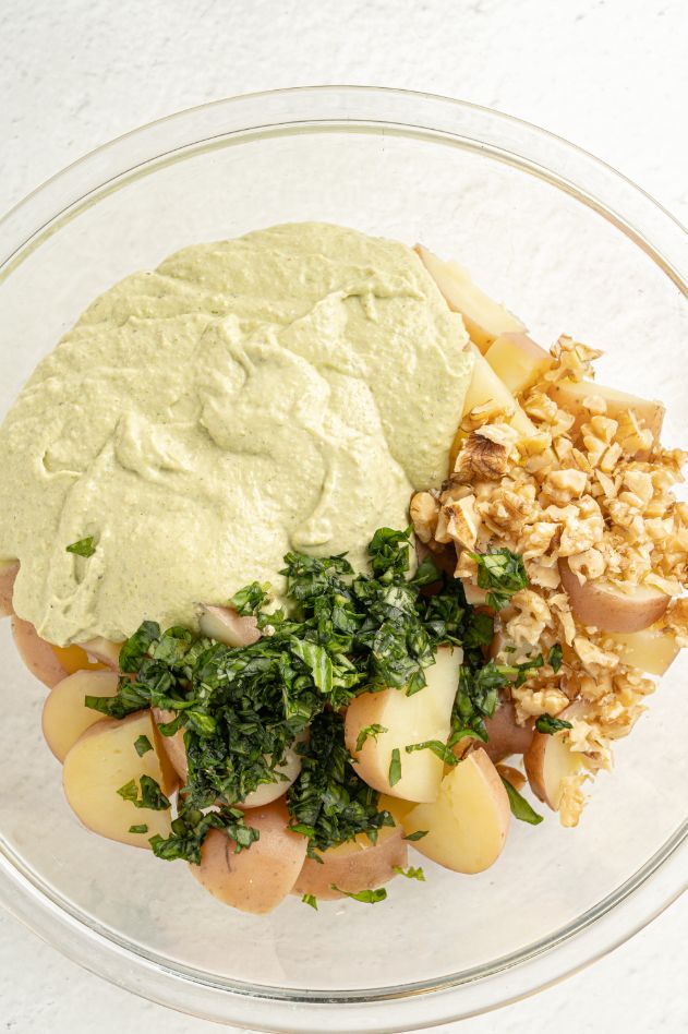 Overhead shot of pesto dressing ingredients added to the bowl of a food processor