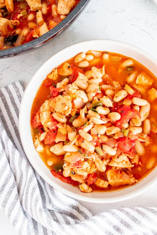 A large white bowl containing a tomato based stew