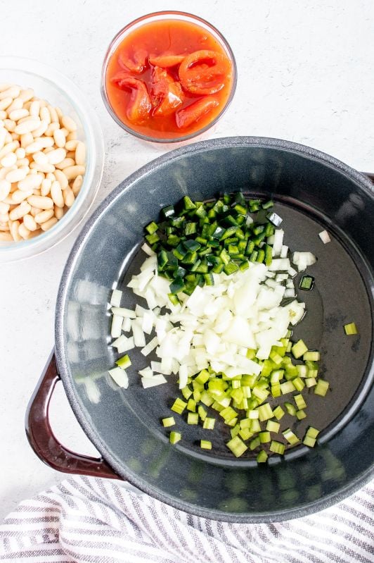 A large heavy based pan with some chopped onions, celery and poblano pepper