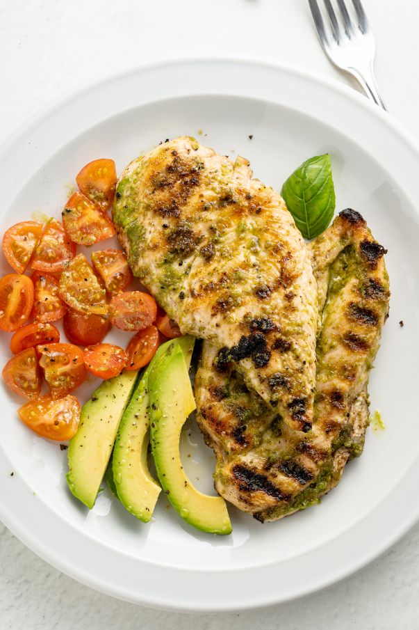 Grilled pesto chicken served with avocado and cherry tomatoes