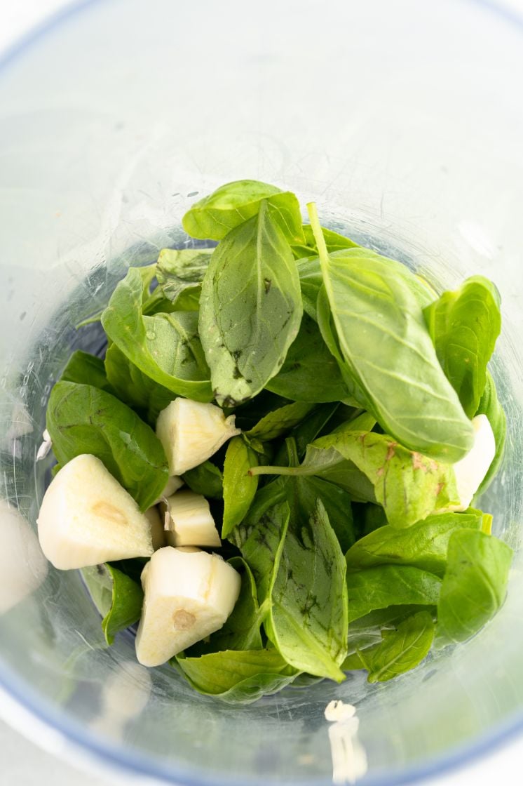Ingredients for a basil pesto in the bowl of a food processor