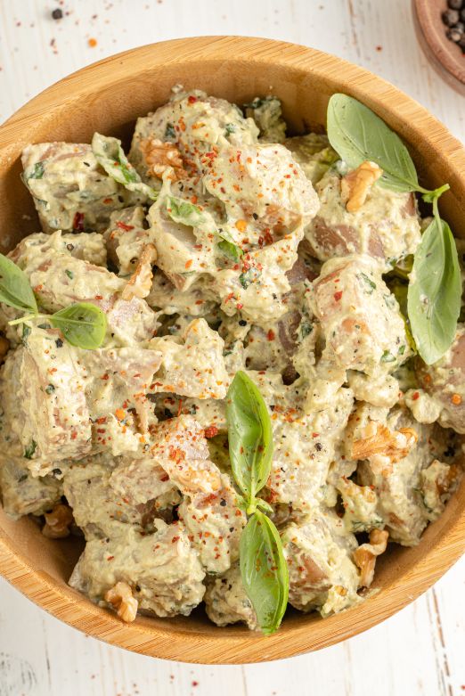Potato salad with pesto served in a wooden bowl with a sprinkle of fresh basil on top
