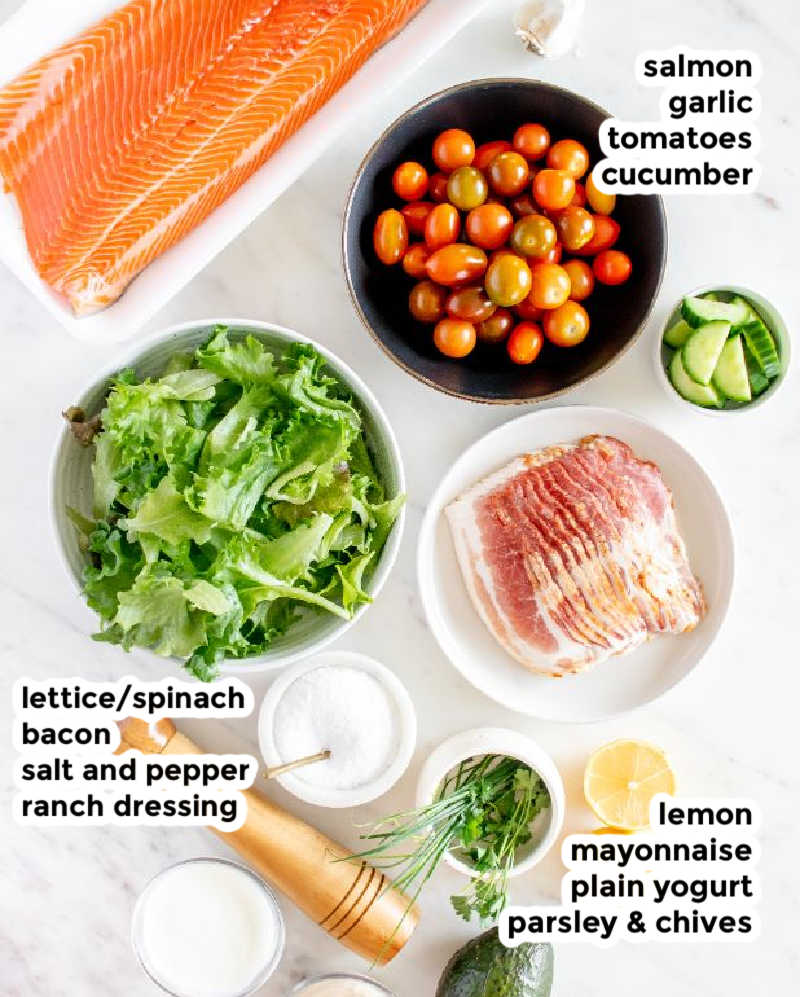 Overhead shot of ingredients needed for a salmon, bacon, lettuce, avocado and tomato salad