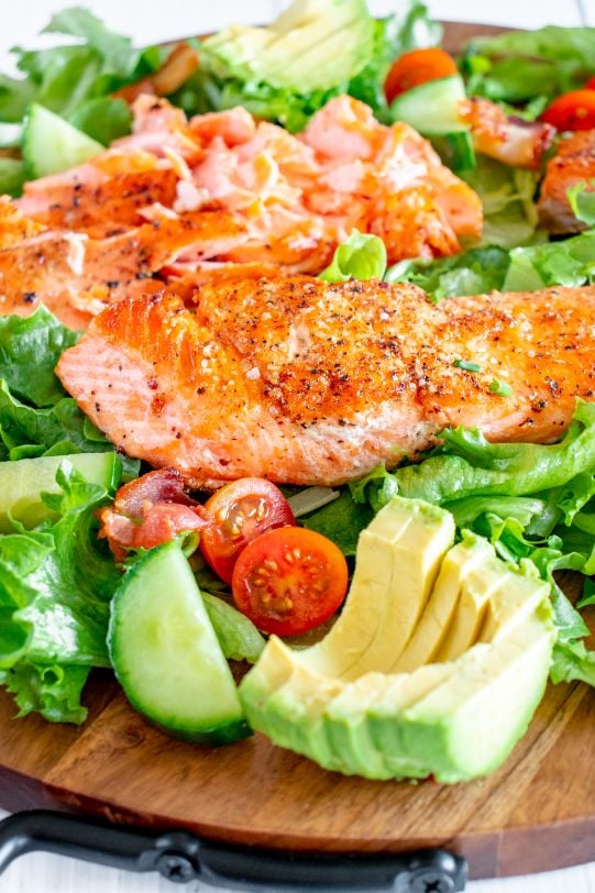 A salmon salad with half a sliced avocado in the foreground