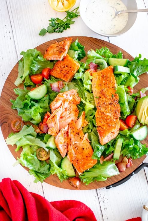 Salmon avocado salad arranged on a large wooden chopping board