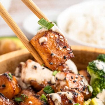 Air fryer salmon bite being picked up from a bowl with some chop sticks