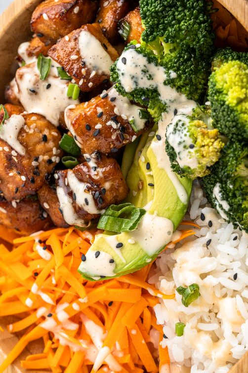 up close shot of a salmon rice bowl with veggies served in a wooden bowl